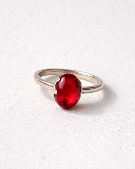 Silver ring with a red gemstone on a white background