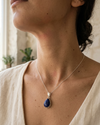Woman wearing a necklace with a blue pendant indoors
