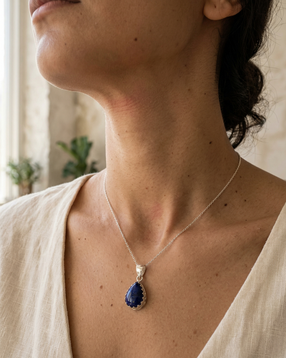 Woman wearing a necklace with a blue pendant indoors
