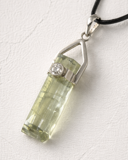 Green crystal pendant with silver setting on a white background