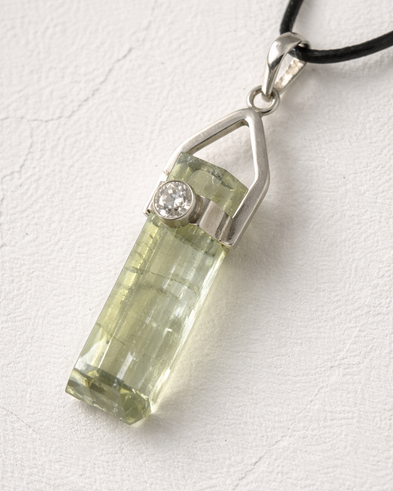 Green crystal pendant with silver setting on a white background
