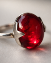 Silver ring with a red gemstone on a gray background