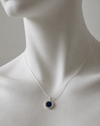Mannequin wearing a necklace with a blue pendant on a neutral background