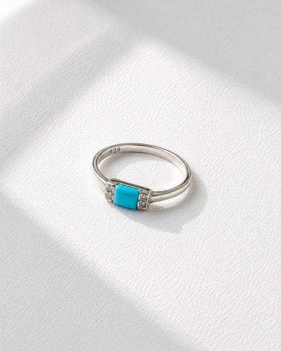 Silver ring with a turquoise stone on a white fabric background