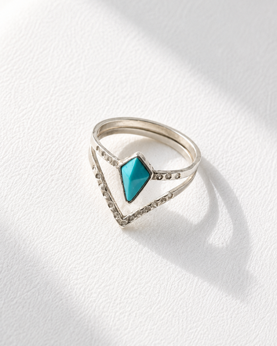 Silver ring with a turquoise gemstone on a white background