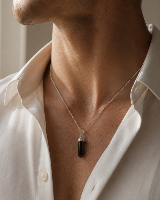 Person wearing a necklace with a pendant against a neutral background
