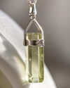 Silver pendant with a green gemstone on a neutral background