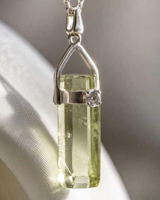 Silver pendant with a green gemstone on a neutral background