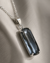 Necklace with a dark gemstone pendant on a beige fabric background