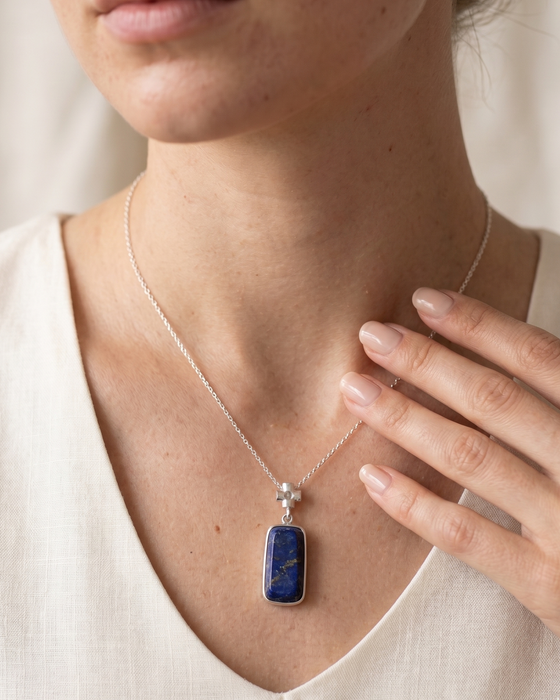 Necklace with a blue pendant worn by a person, with a neutral background