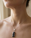 Necklace with a pendant worn by a person, with a neutral background