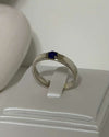 Silver ring with a blue gemstone on a white box
