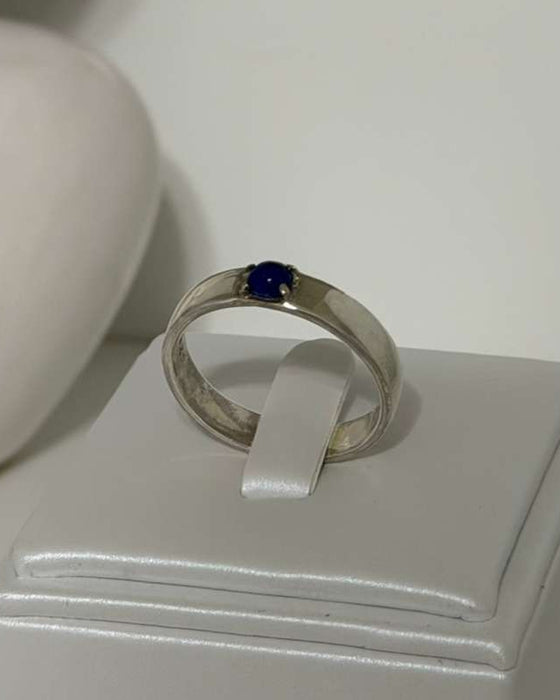 Silver ring with a blue gemstone on a white box