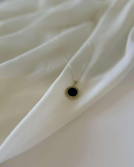 Close-up of a black earring on a white shirt