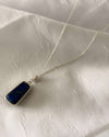 Necklace with a blue pendant on a white fabric background