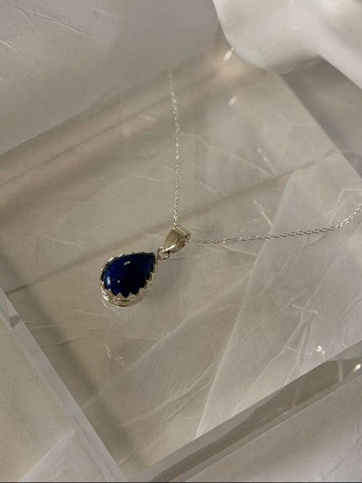 Blue teardrop pendant necklace on a mannequin head with a white background