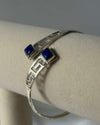 Silver bracelet with blue stones on a mannequin arm against a gray background