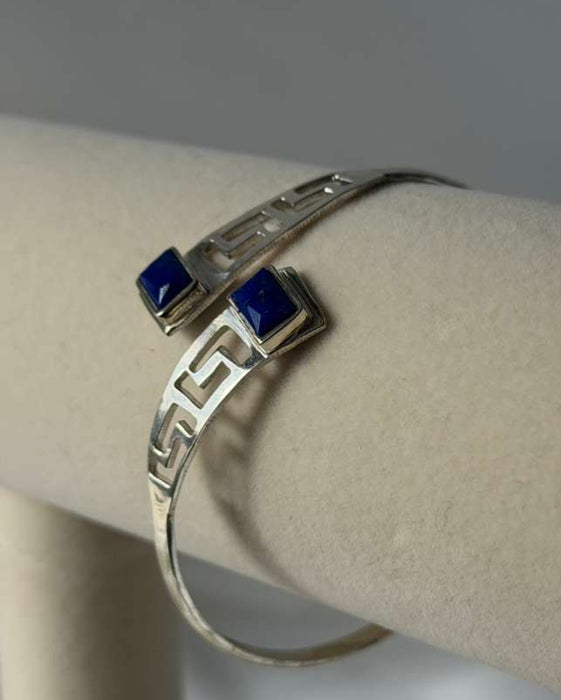 Silver bracelet with blue stones on a mannequin arm against a gray background