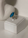 Ring with a blue stone on a white stand