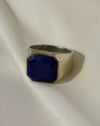 Silver ring with a blue stone on a white fabric background