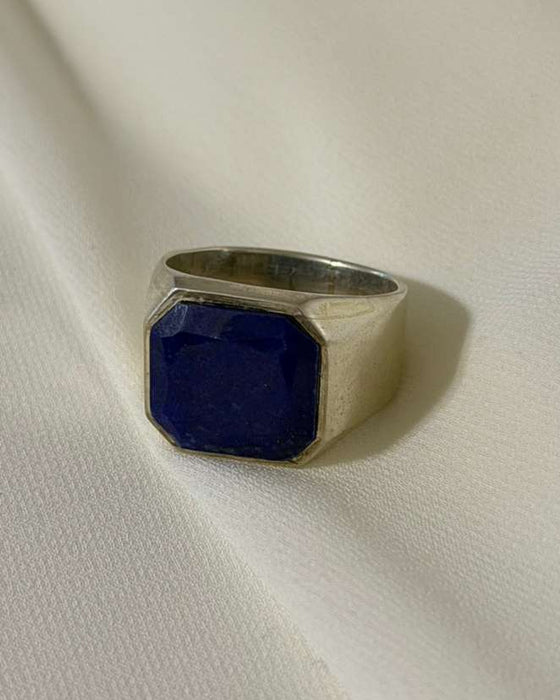 Silver ring with a blue stone on a white fabric background