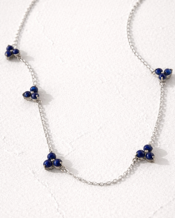 Silver necklace with blue beads on a white background