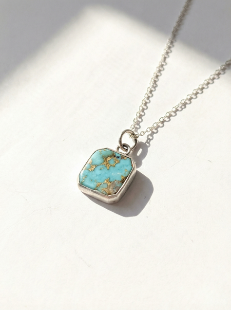 Necklace with a turquoise pendant on a light background