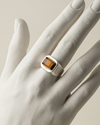 Silver ring with a rectangular gemstone on a mannequin hand against a neutral background