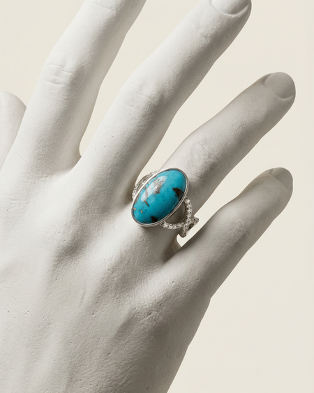 Turquoise ring with silver band on a white hand model