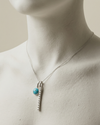 Necklace with a turquoise pendant and silver chain on a mannequin.