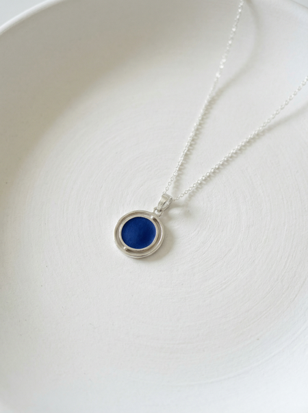 Silver necklace with a blue pendant on a white background