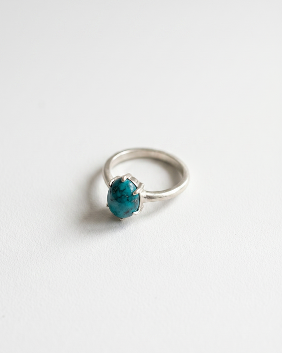 Silver ring with a blue gemstone on a white background