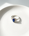 Silver ring with a blue gemstone on a white surface
