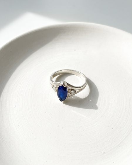 Silver ring with a blue gemstone on a white surface