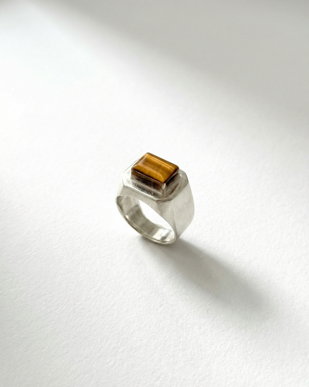 Silver ring with a square brown gemstone on a white background